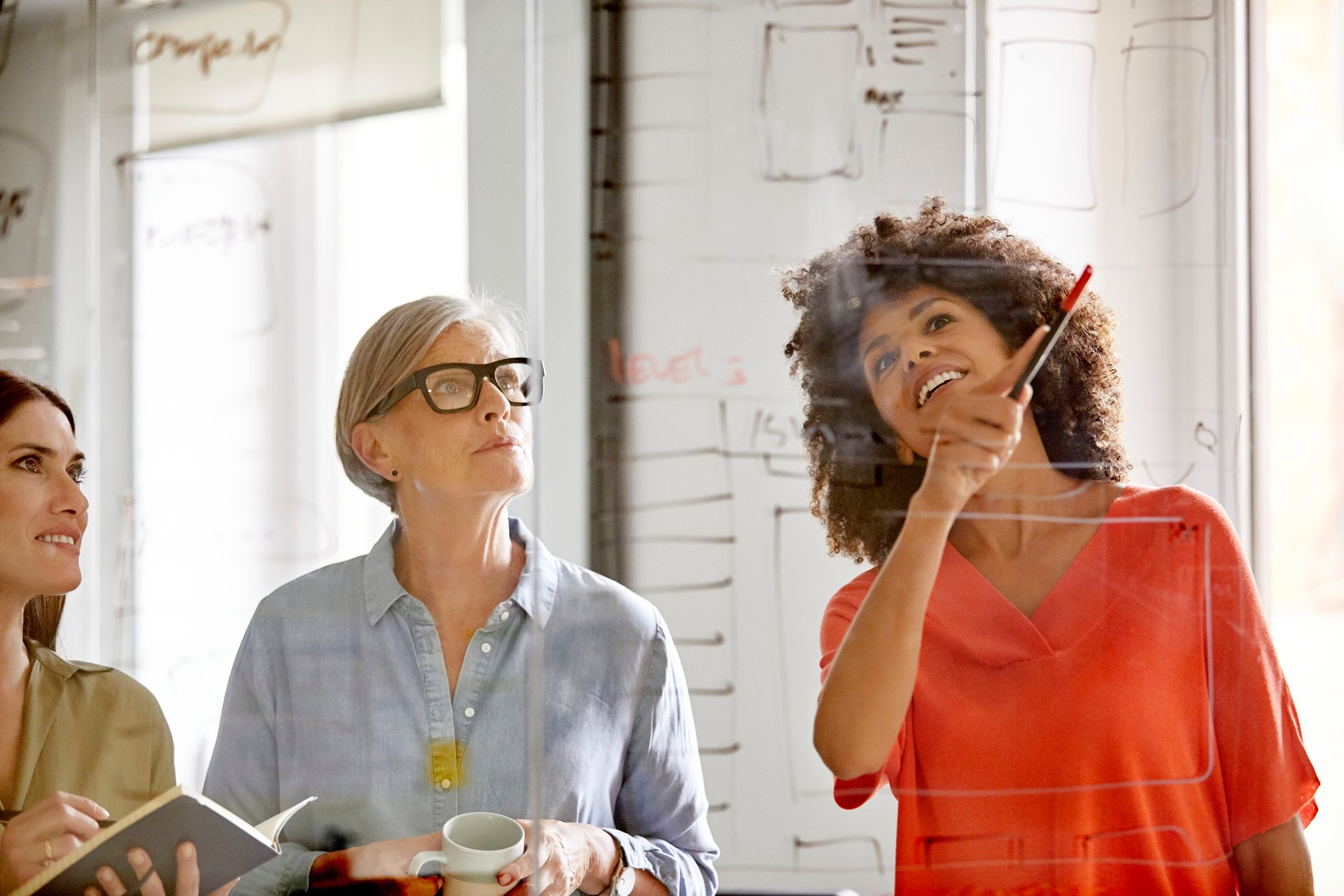 Businesswomen Discussing Plan On Glass Wall